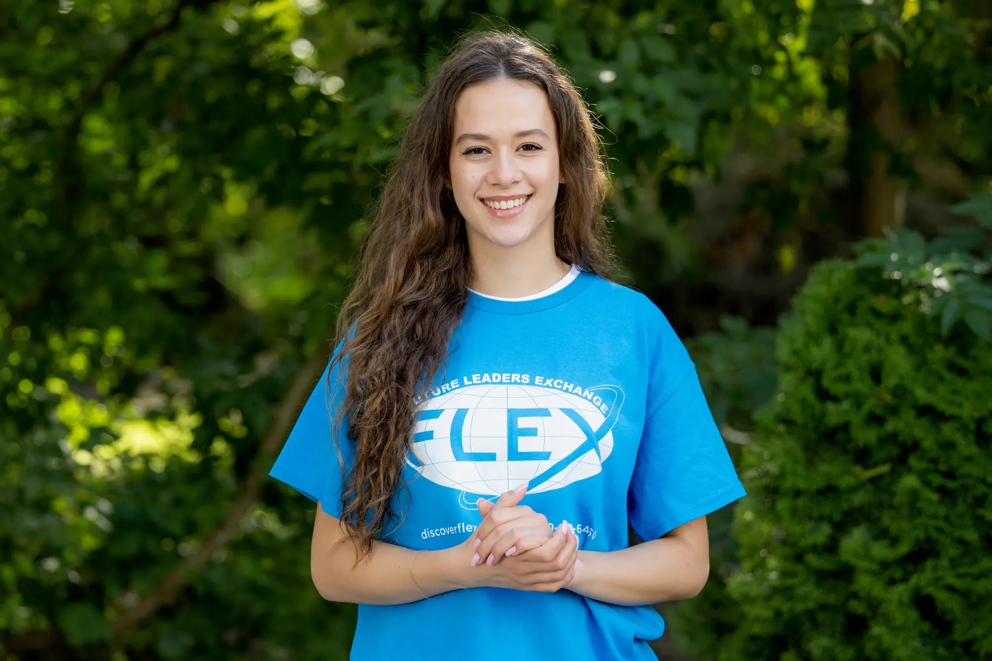 Aleksandra w niebieskiej koszulce programu FLEX, uśmiechnięta, na tle zieleni