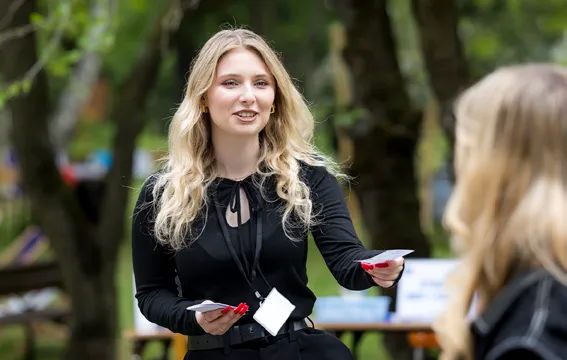 Małgorzata rozmawia z przechodniem w parku i wręcza mu ulotkę