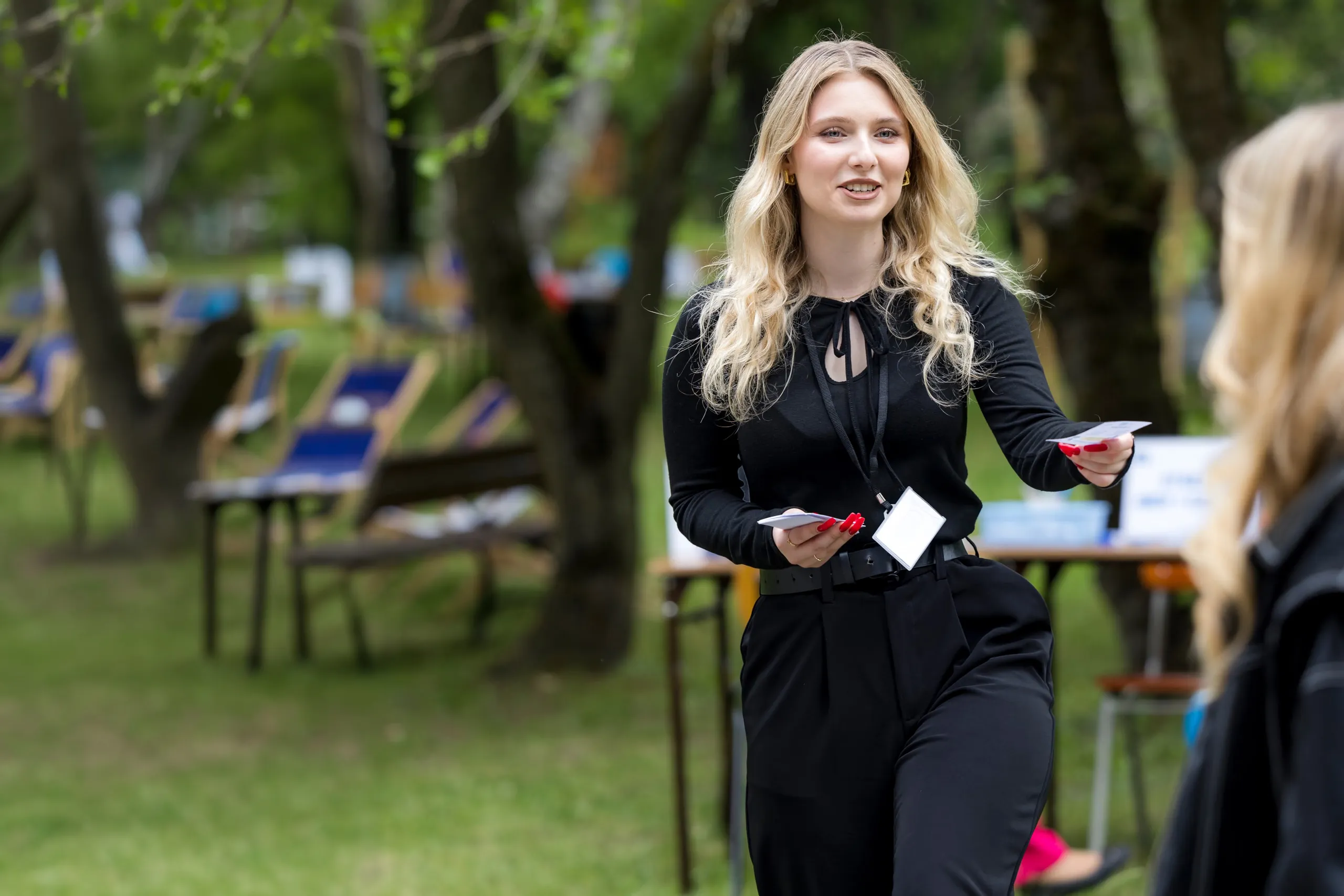 Małgorzata rozmawia z przechodniem w parku i wręcza mu ulotkę